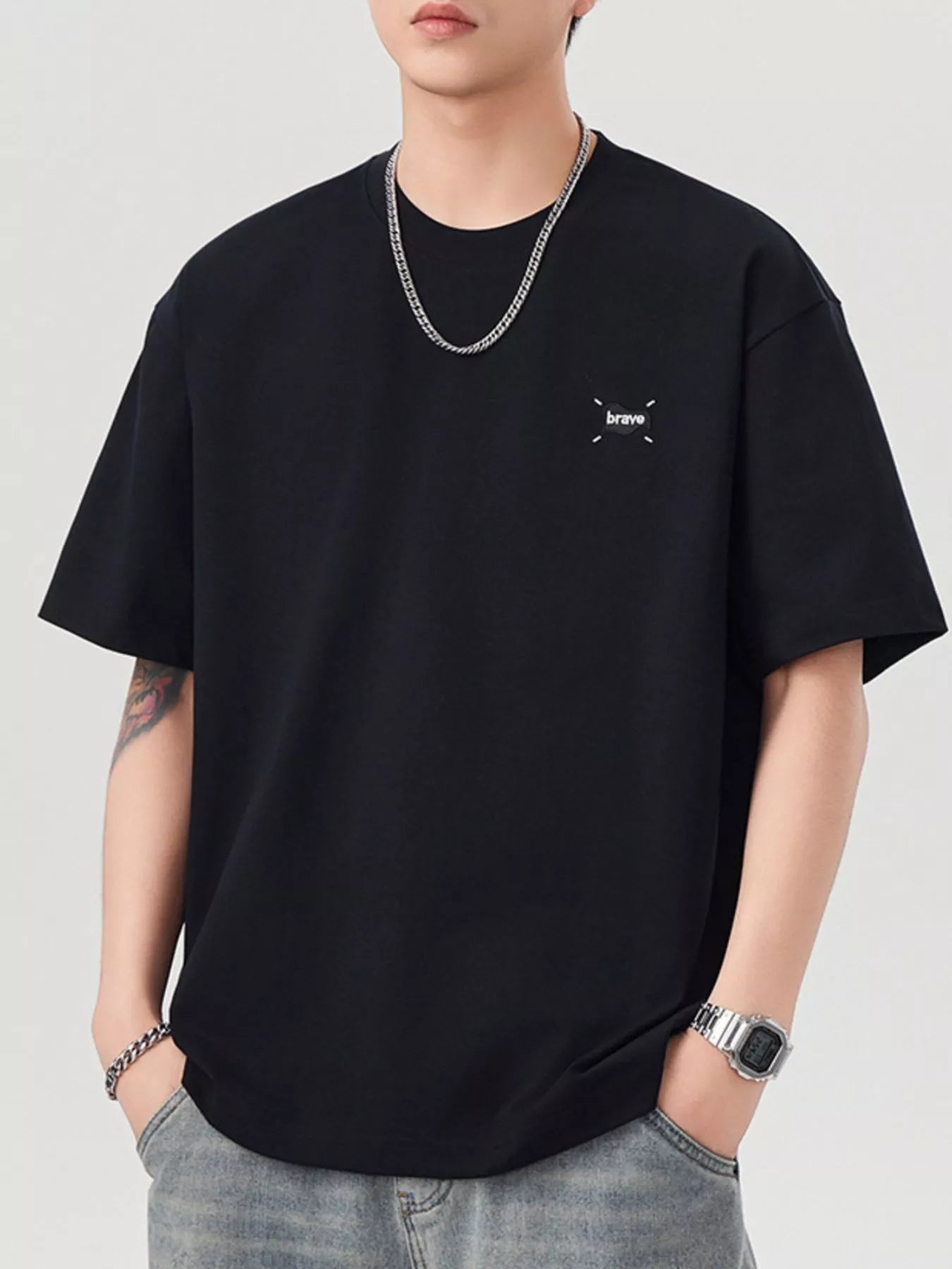 Person wearing a black t-shirt with a small logo on a plain background