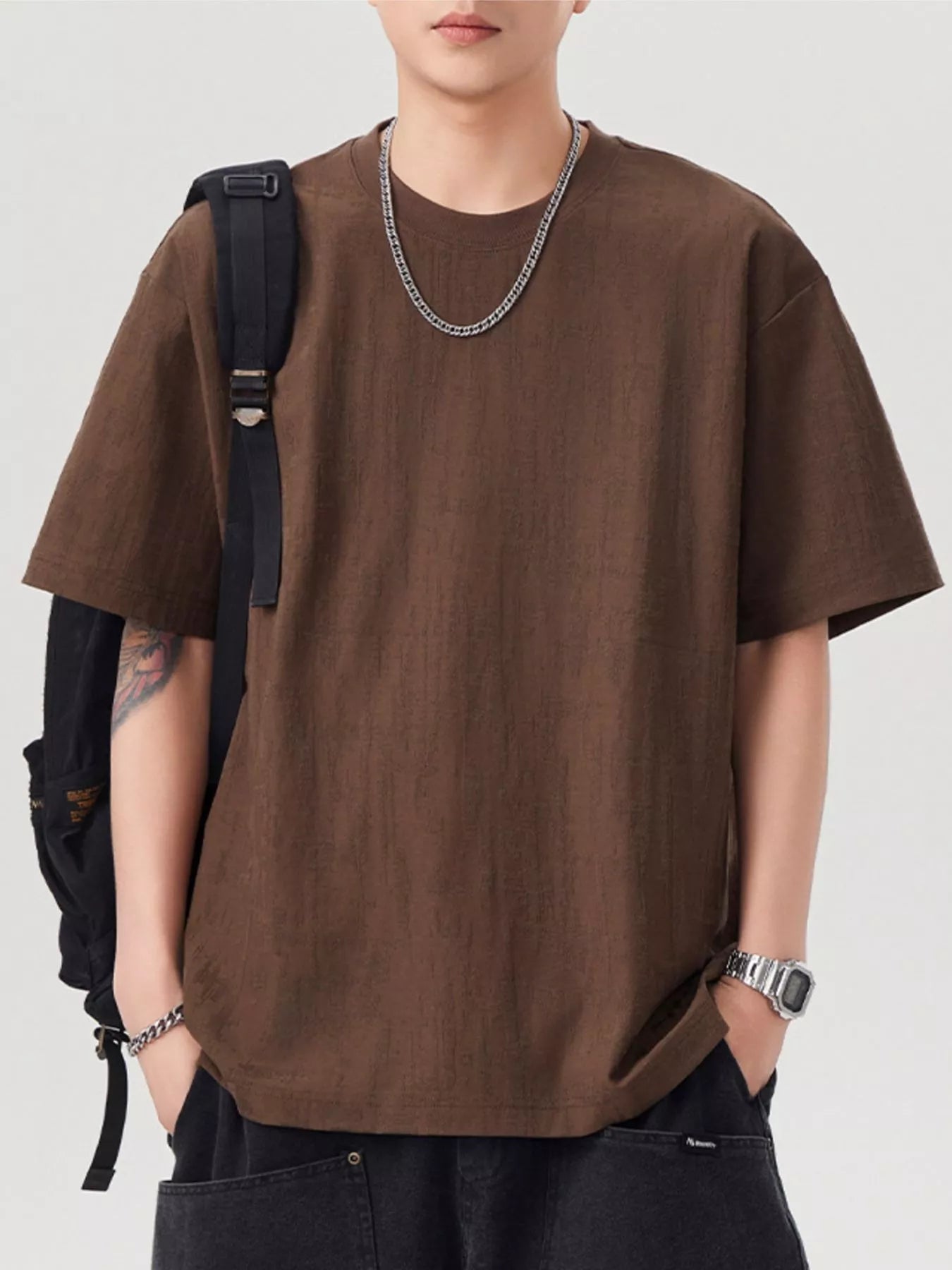 Person wearing a brown oversized t-shirt with a plain background