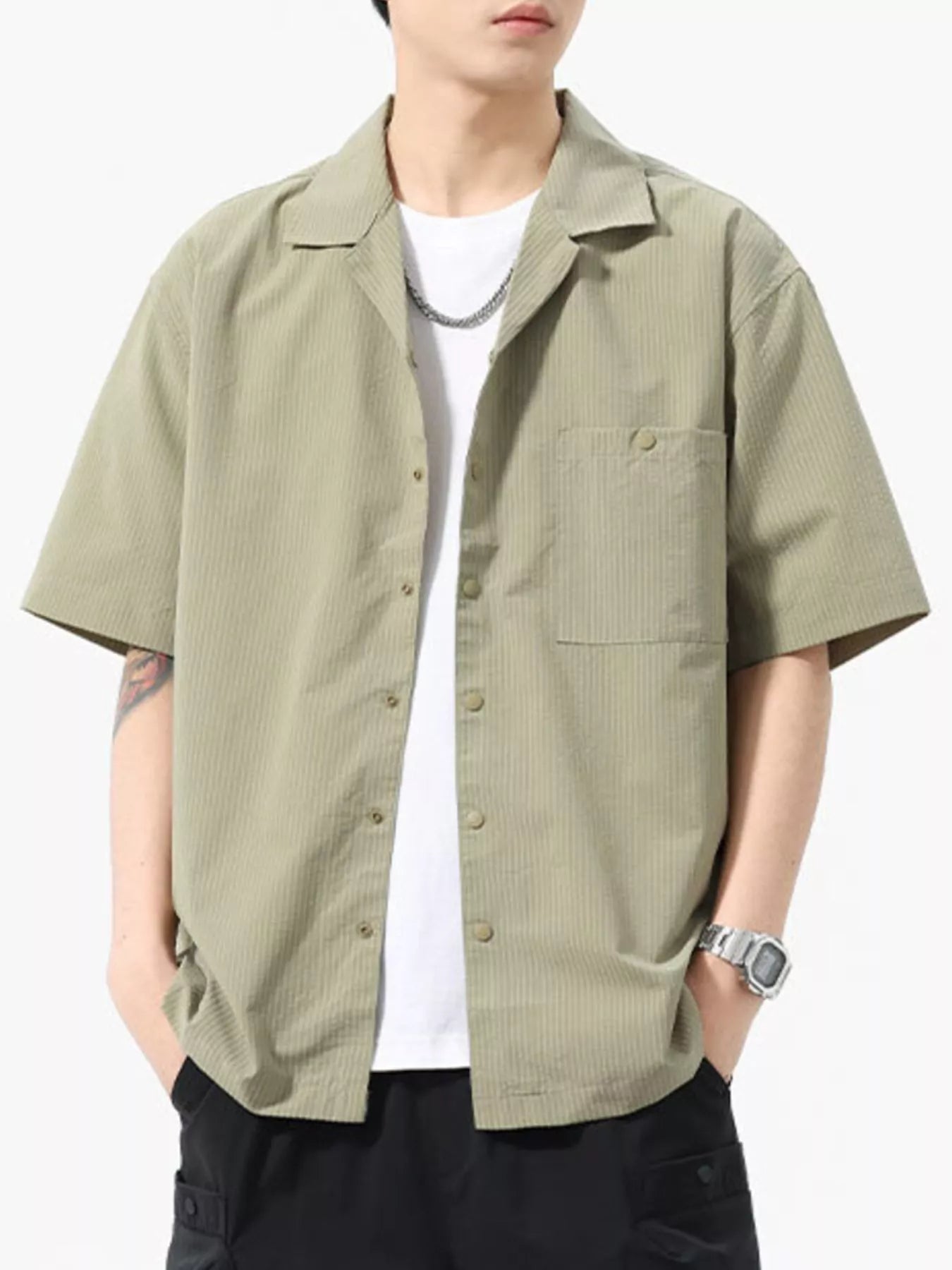 Person wearing a light green short-sleeve shirt over a white t-shirt on a white background