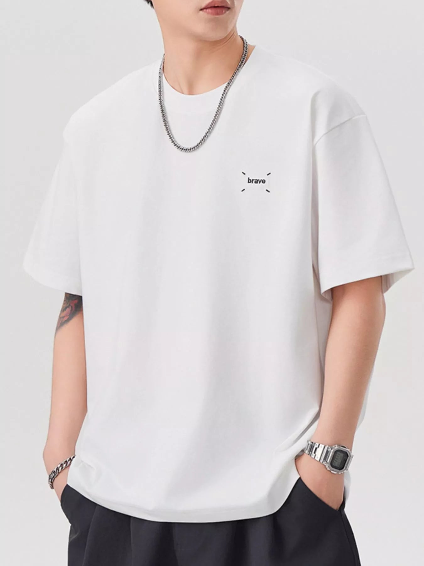 Person wearing a white t-shirt with a small logo on a plain background