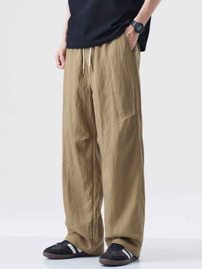 Person wearing beige wide-leg pants and black shoes on a white background