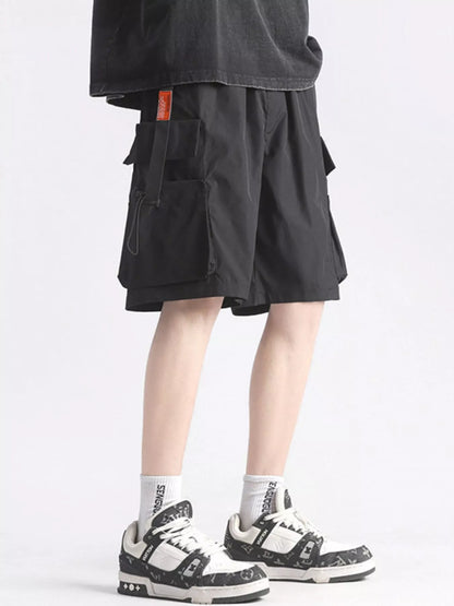 Person wearing black cargo shorts and white sneakers on a light gray background