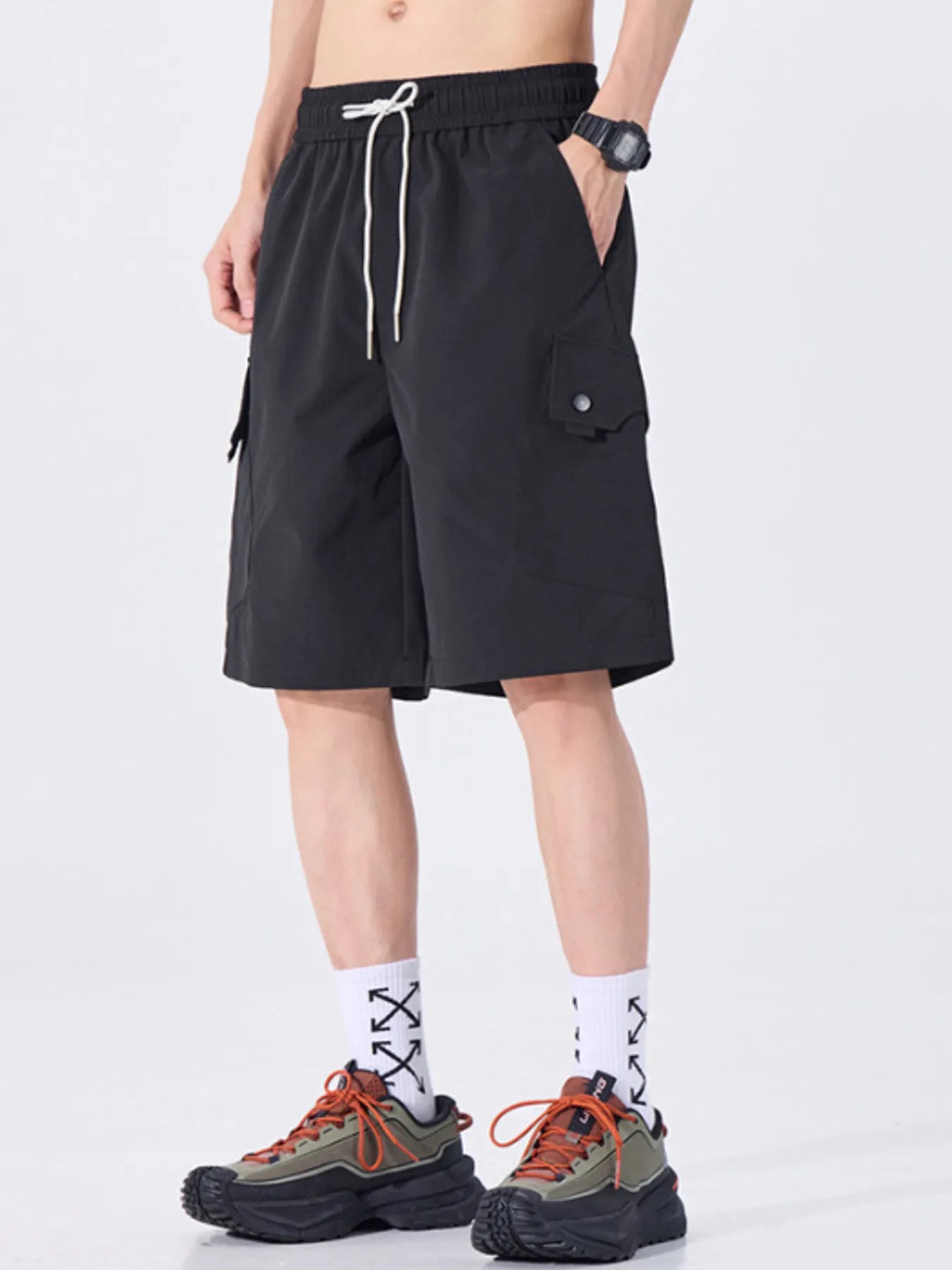 Person wearing black cargo shorts on a white background
