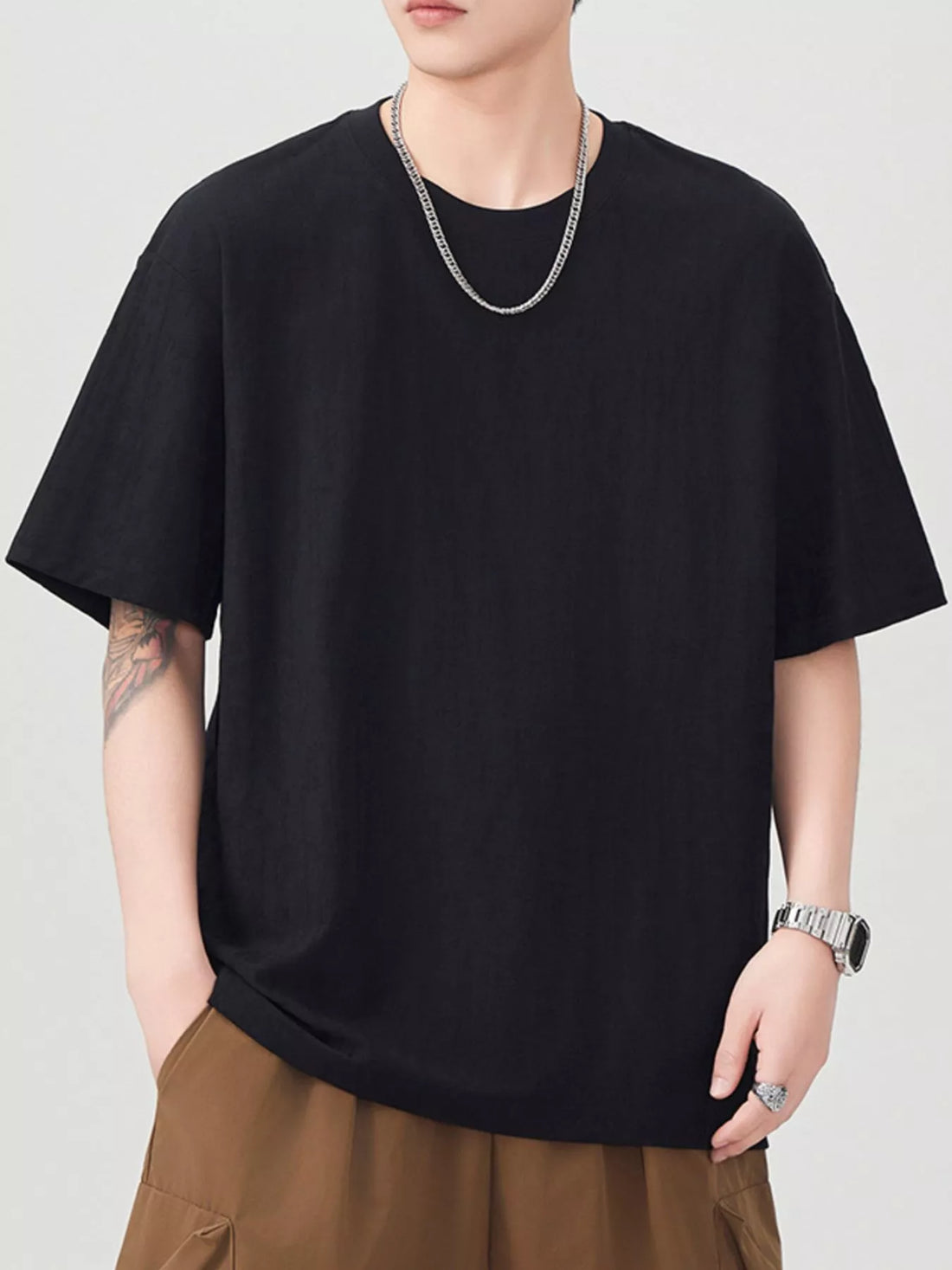 Person wearing a black t-shirt and brown pants on a plain background