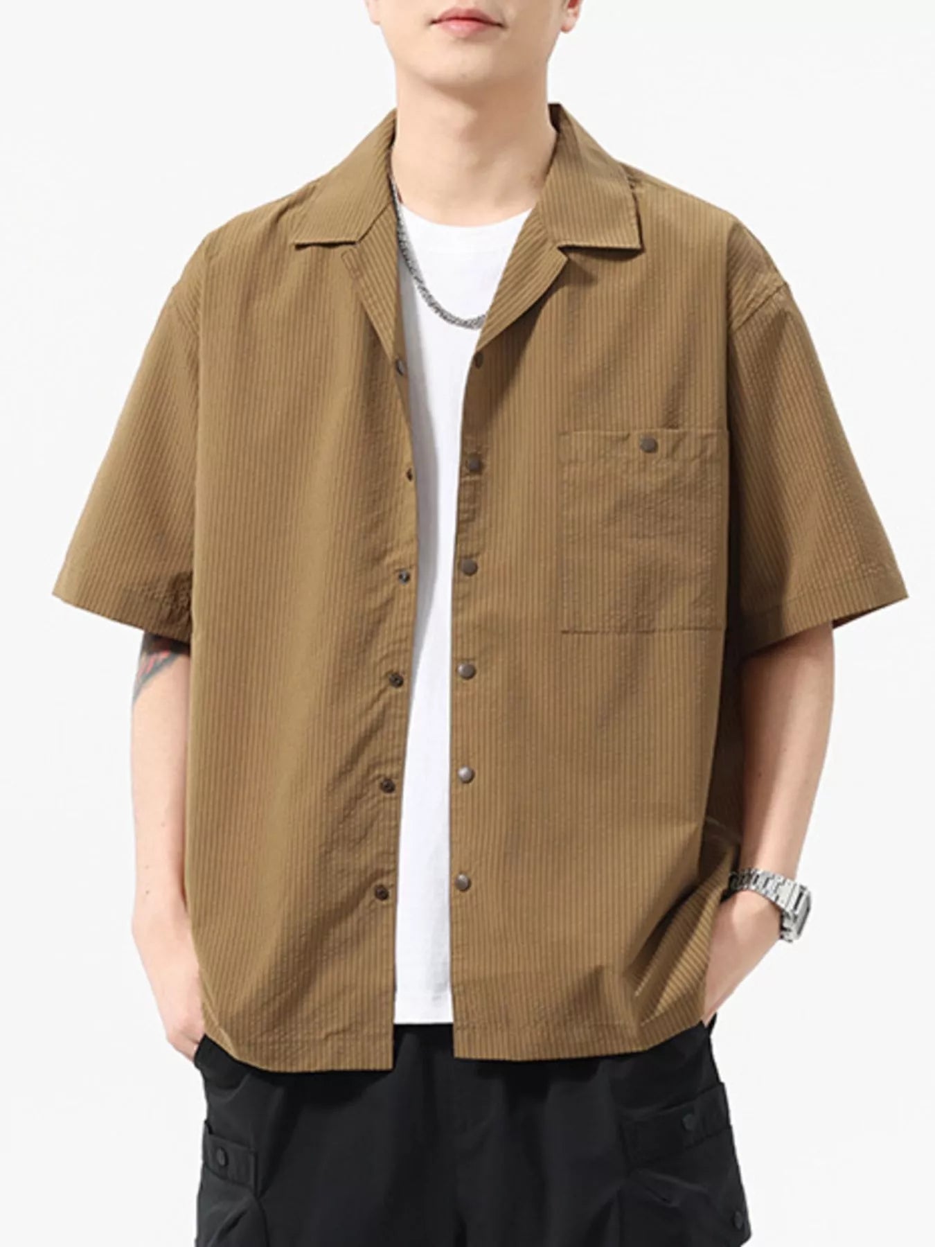 Person wearing a brown short-sleeve shirt over a white t-shirt on a white background