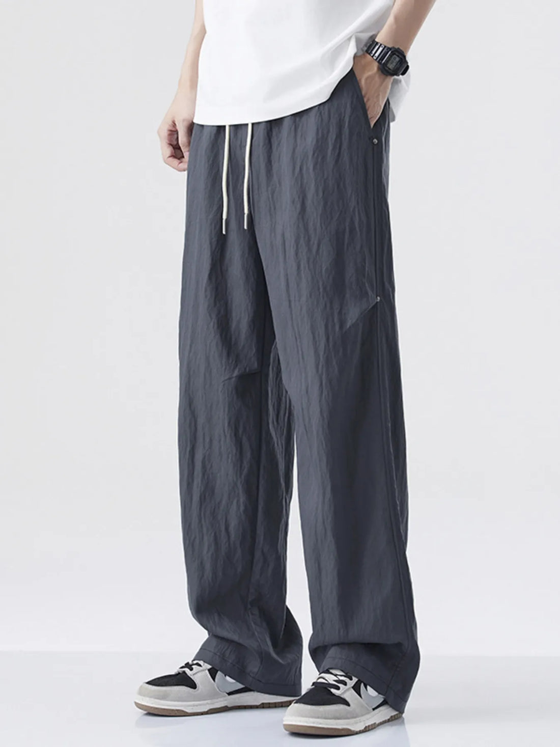 Person wearing gray wide-leg pants and a white shirt on a white background