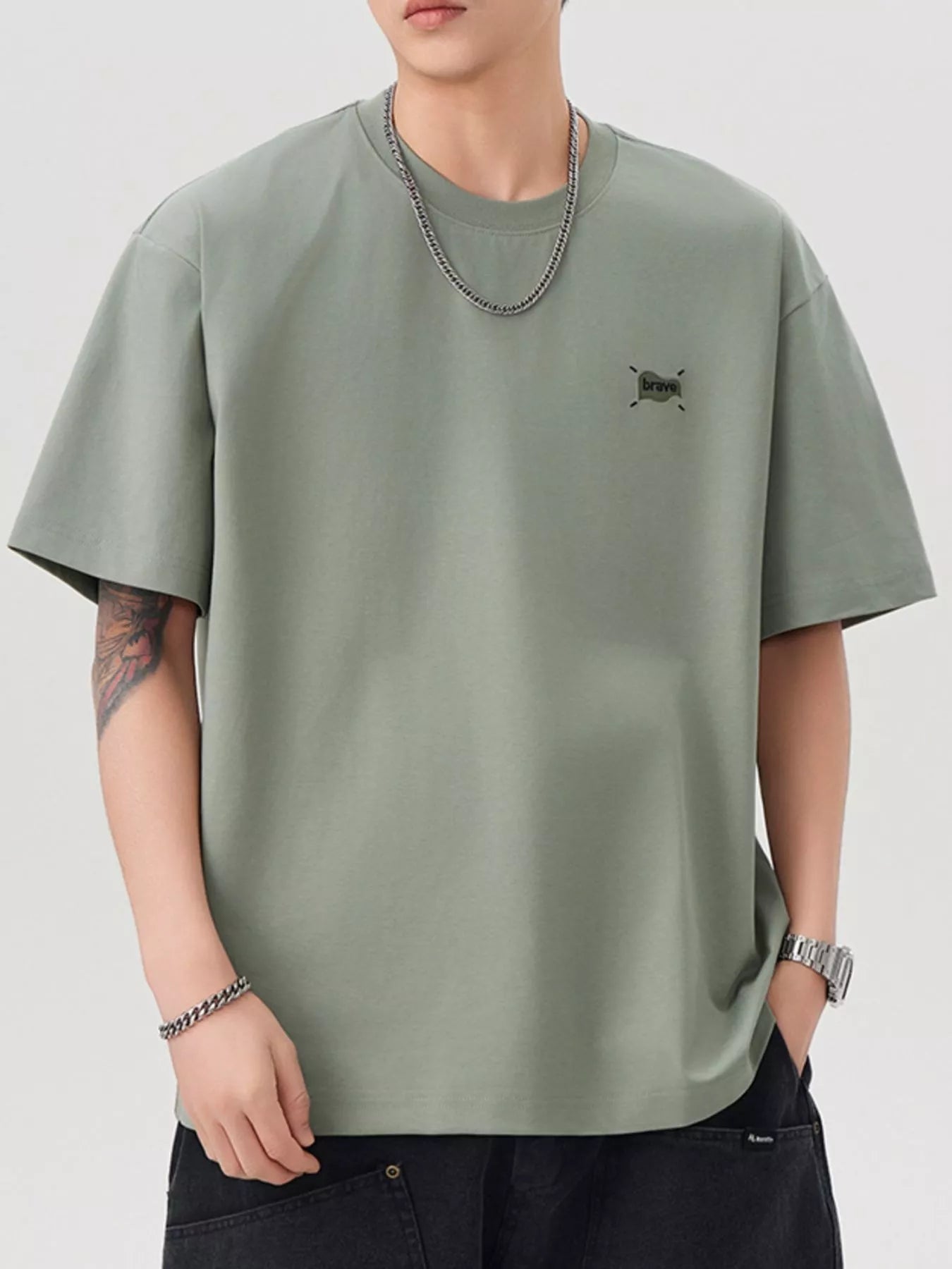 Person wearing a green t-shirt with a small logo on a white background