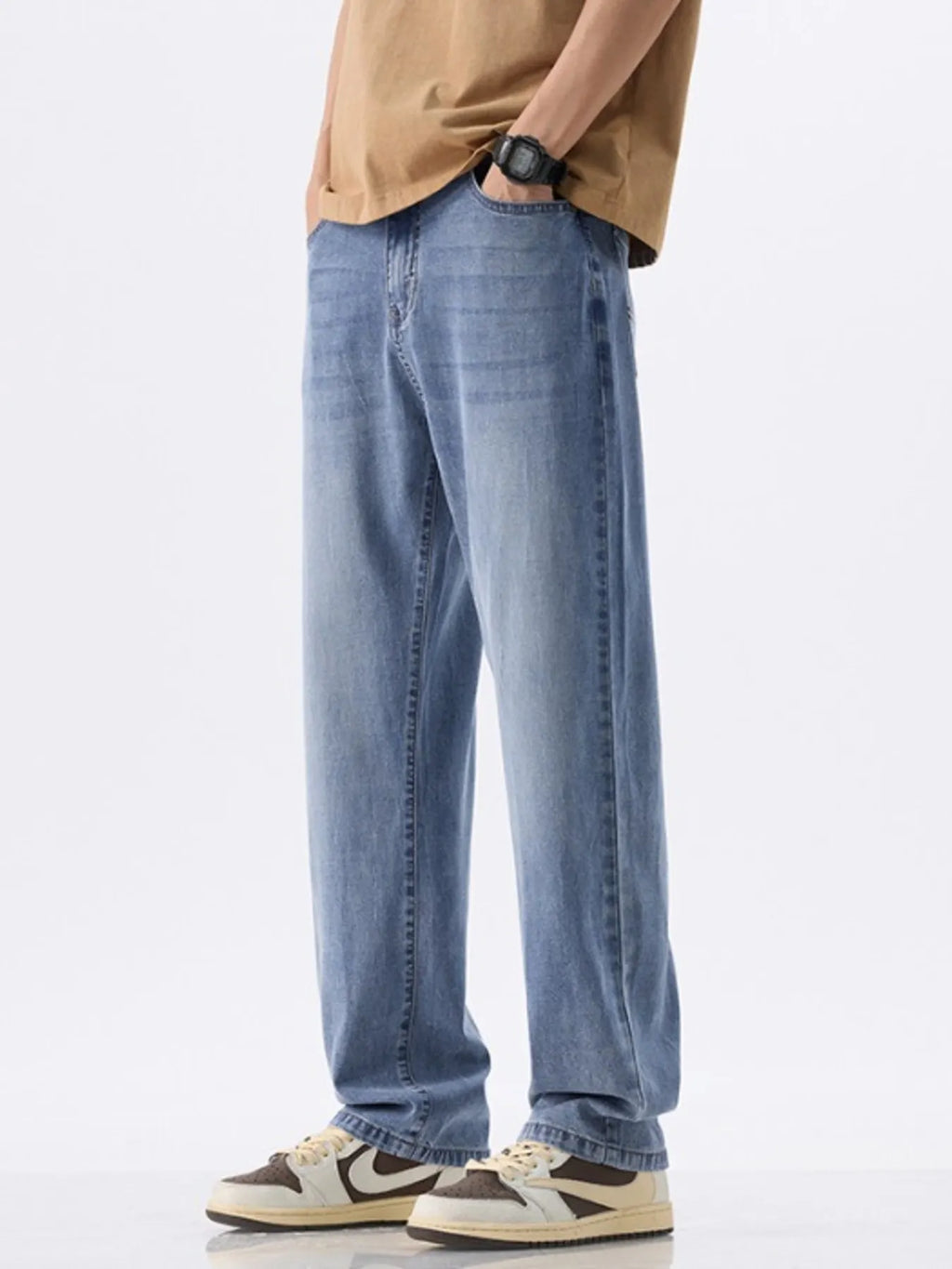 Person wearing light blue jeans and a beige shirt on a white background