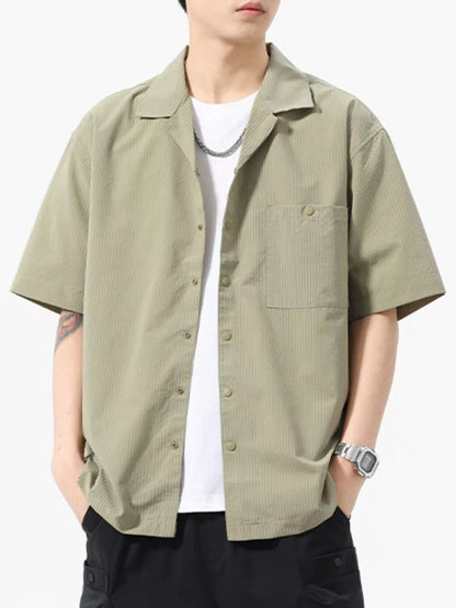 Person wearing a light green short-sleeve shirt over a white t-shirt on a white background