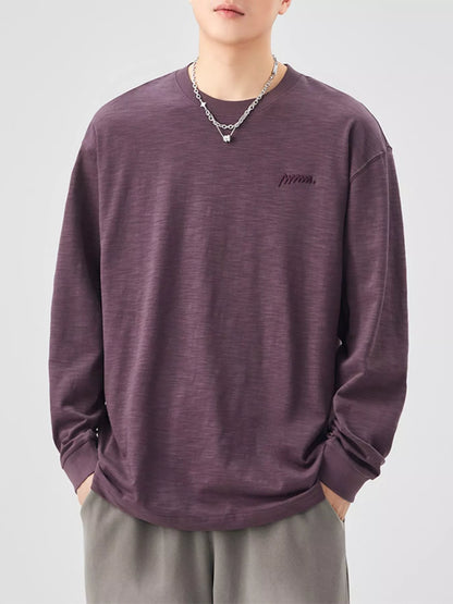 Person wearing a purple long-sleeve shirt with a logo on a plain background
