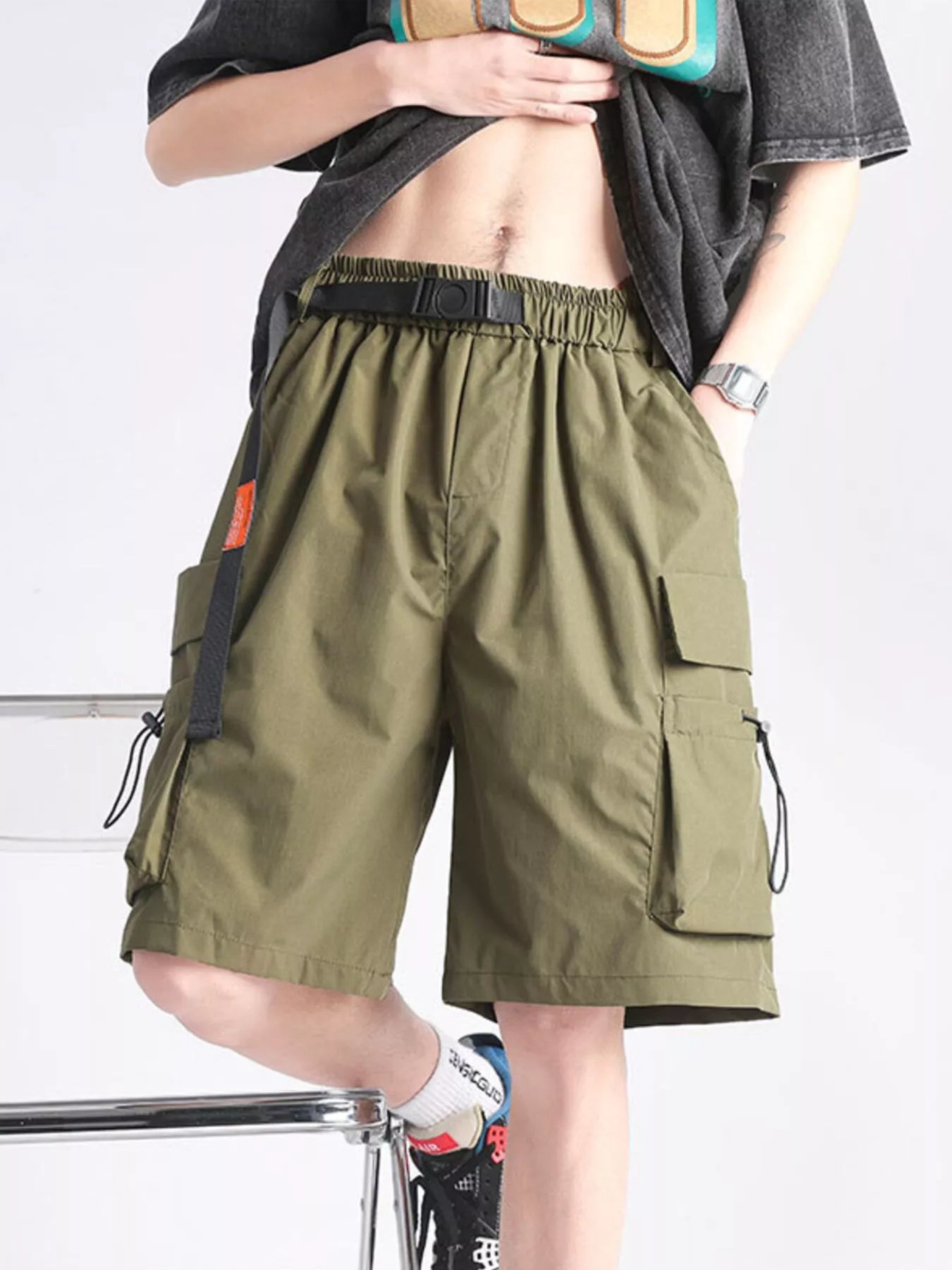 Person wearing olive green cargo shorts on a white background