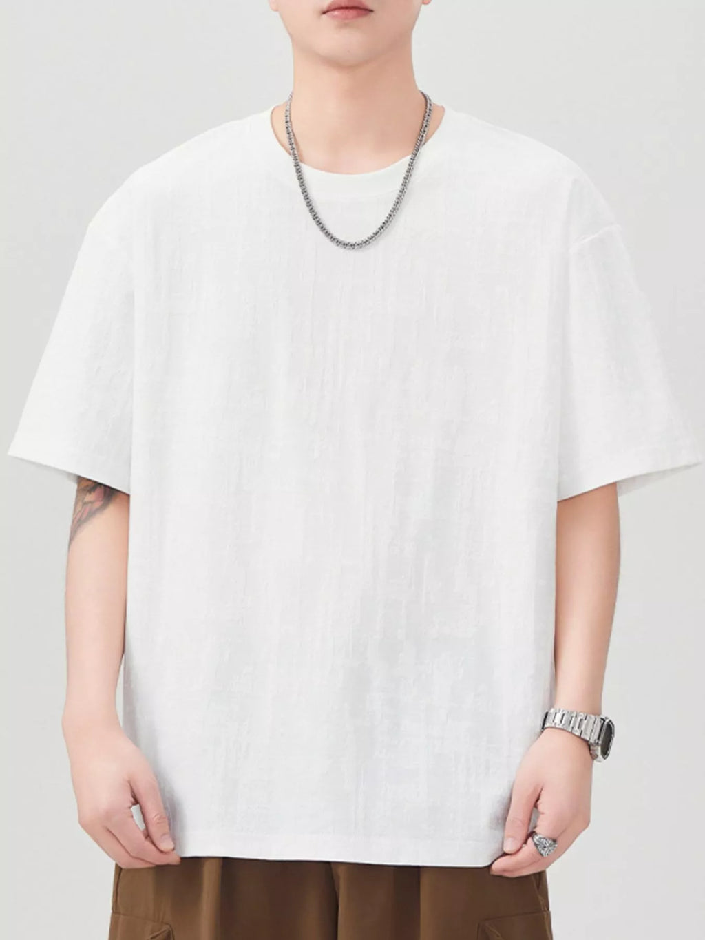 Person wearing a plain white t-shirt on a light gray background