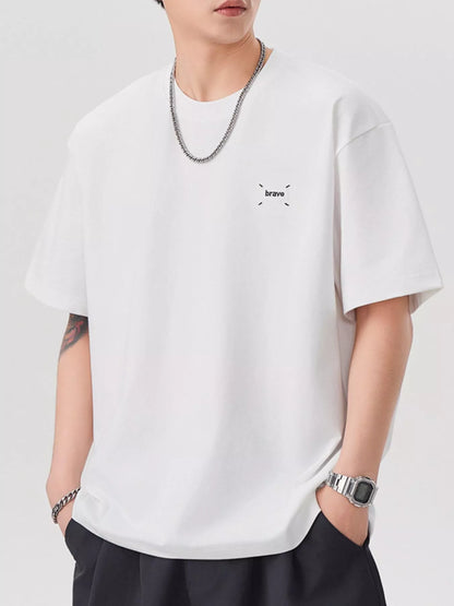 Person wearing a white t-shirt with a small logo on a plain background